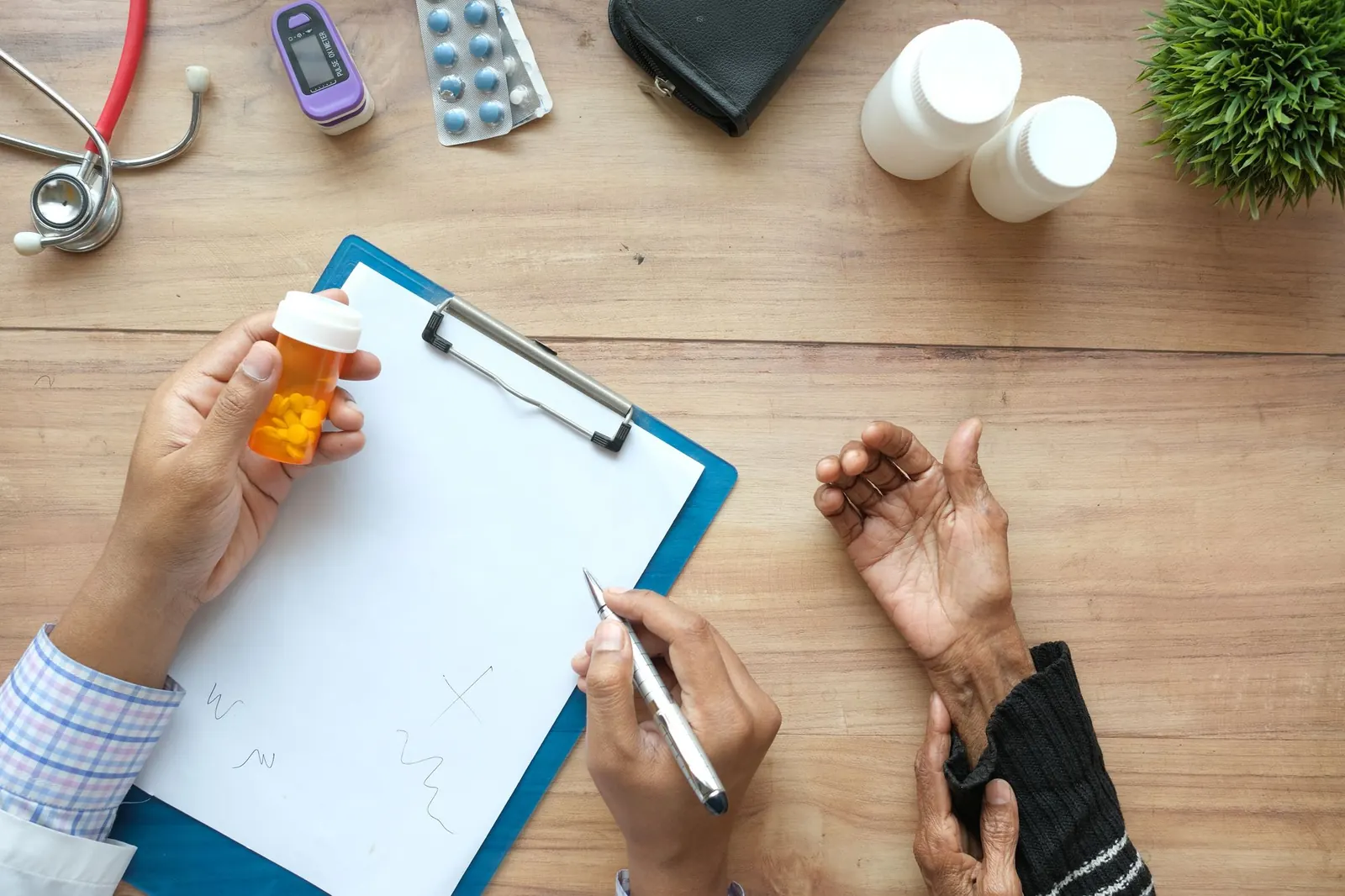 Doctor holding a pill bottle and writing notes while consulting with an older patient across the desk